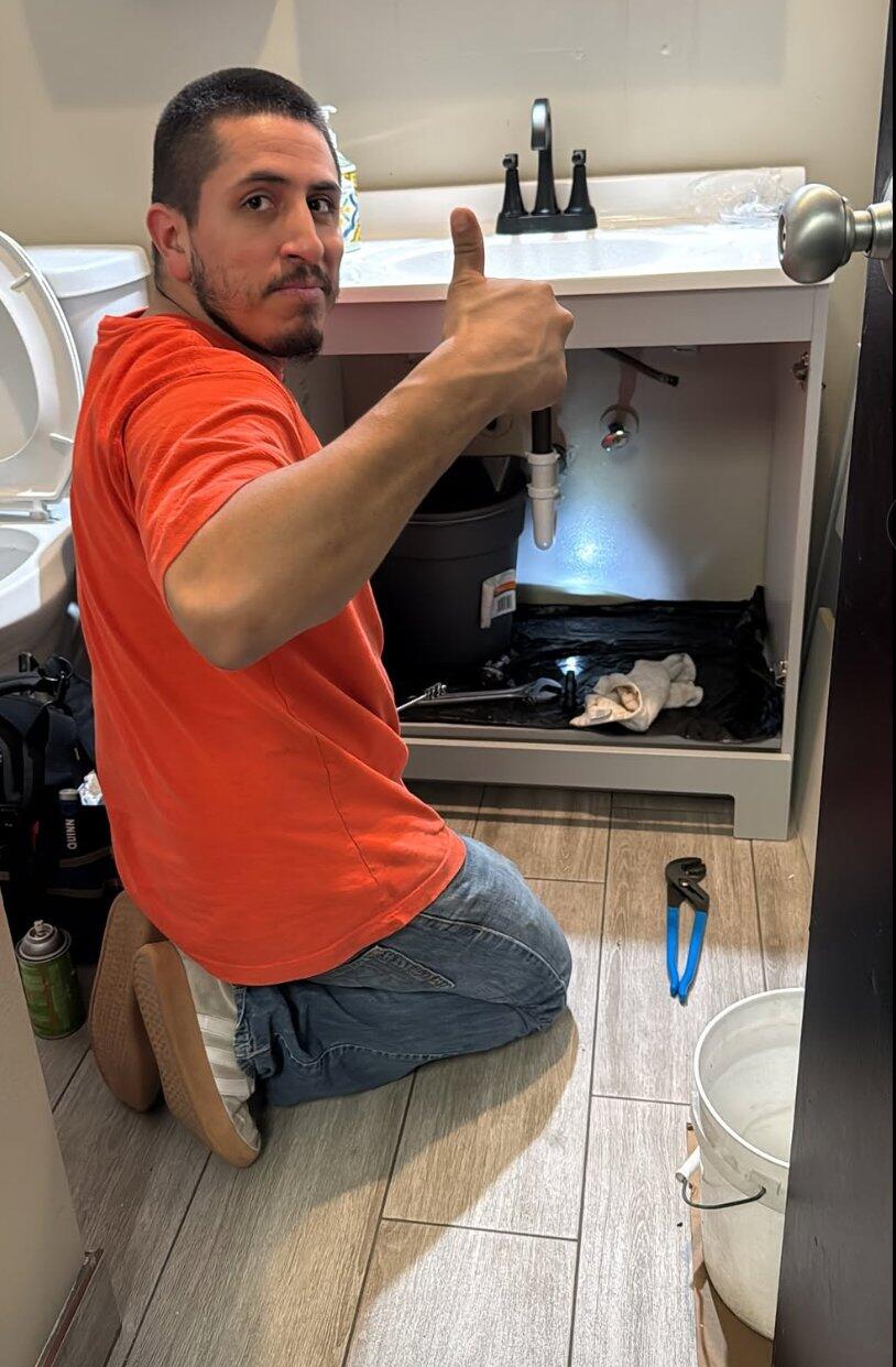 Daniel Muñoz working beneath a bathroom sink